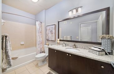 Upscale bathroom with modern wood-accented vanity sink and shower tub at Market Station luxury apartments in Kansas City, MO