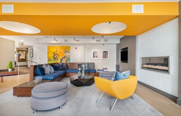 Clubhouse lounge space with couches, chairs, fireplace and big screen TV at Market Station luxury apartments in Kansas City, MO