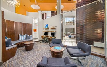 Business center with work stations and lounge seating area with tables at Market Station luxury apartments in Kansas City, MO