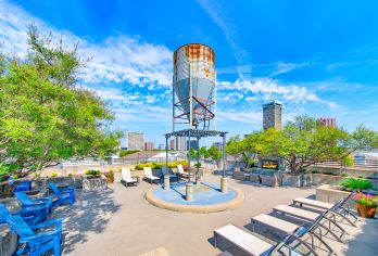 Rooftop terrace with an outdoor fireplace lounge area with chairs and skyline views at MAA Heights luxury apartments in Dallas, TX