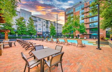 Swimming pool with lounge chairs and shaded patio tables at MAA Heights luxury apartments in Dallas, TX