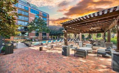 Poolside seating area with a pergola on a brick patio at MAA Heights luxury apartments in Dallas, TX