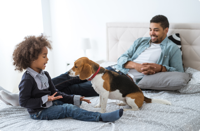 Man and daughter on the bed with their dog