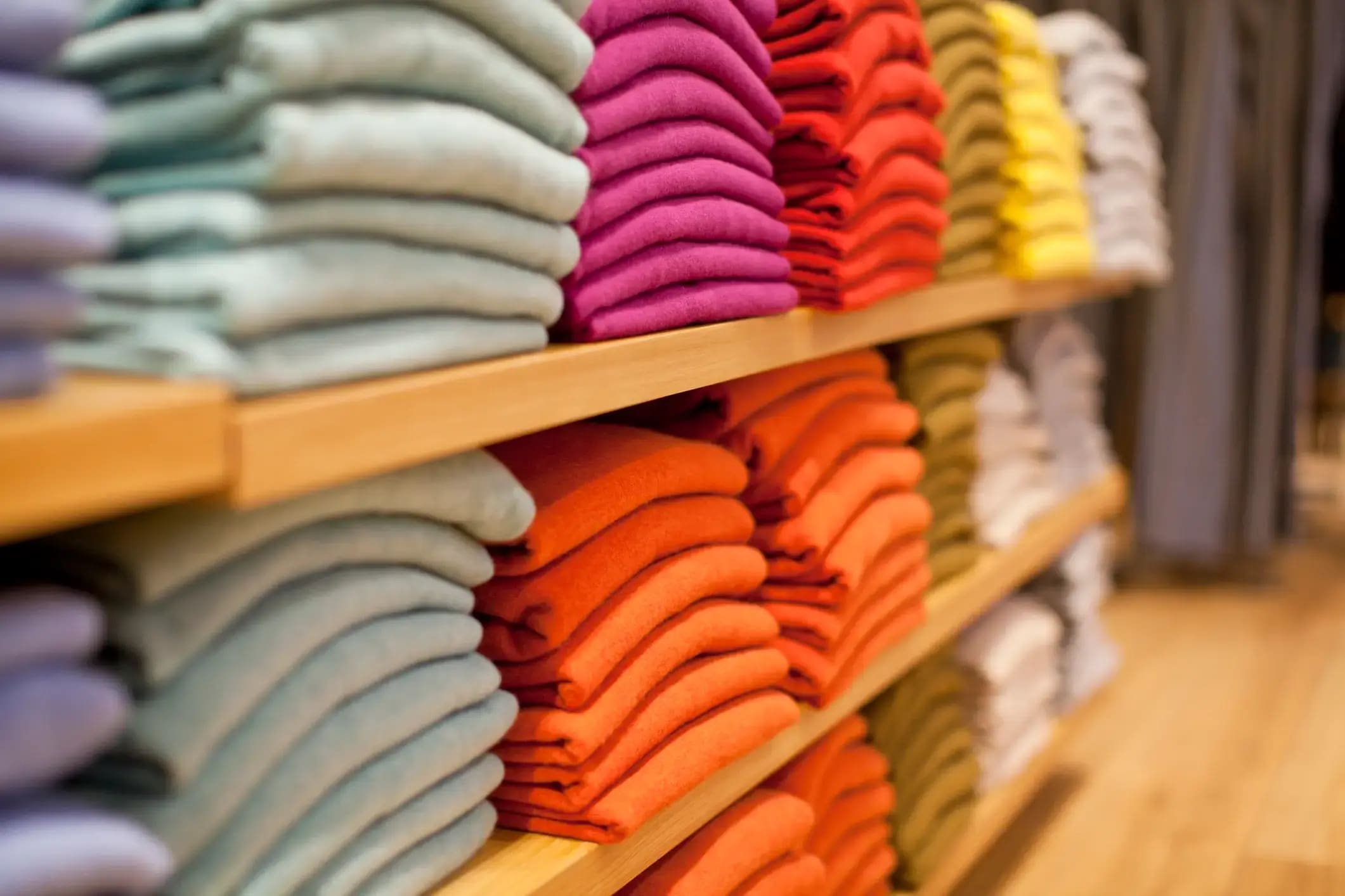 Piles of folded jumpers in a clothing store