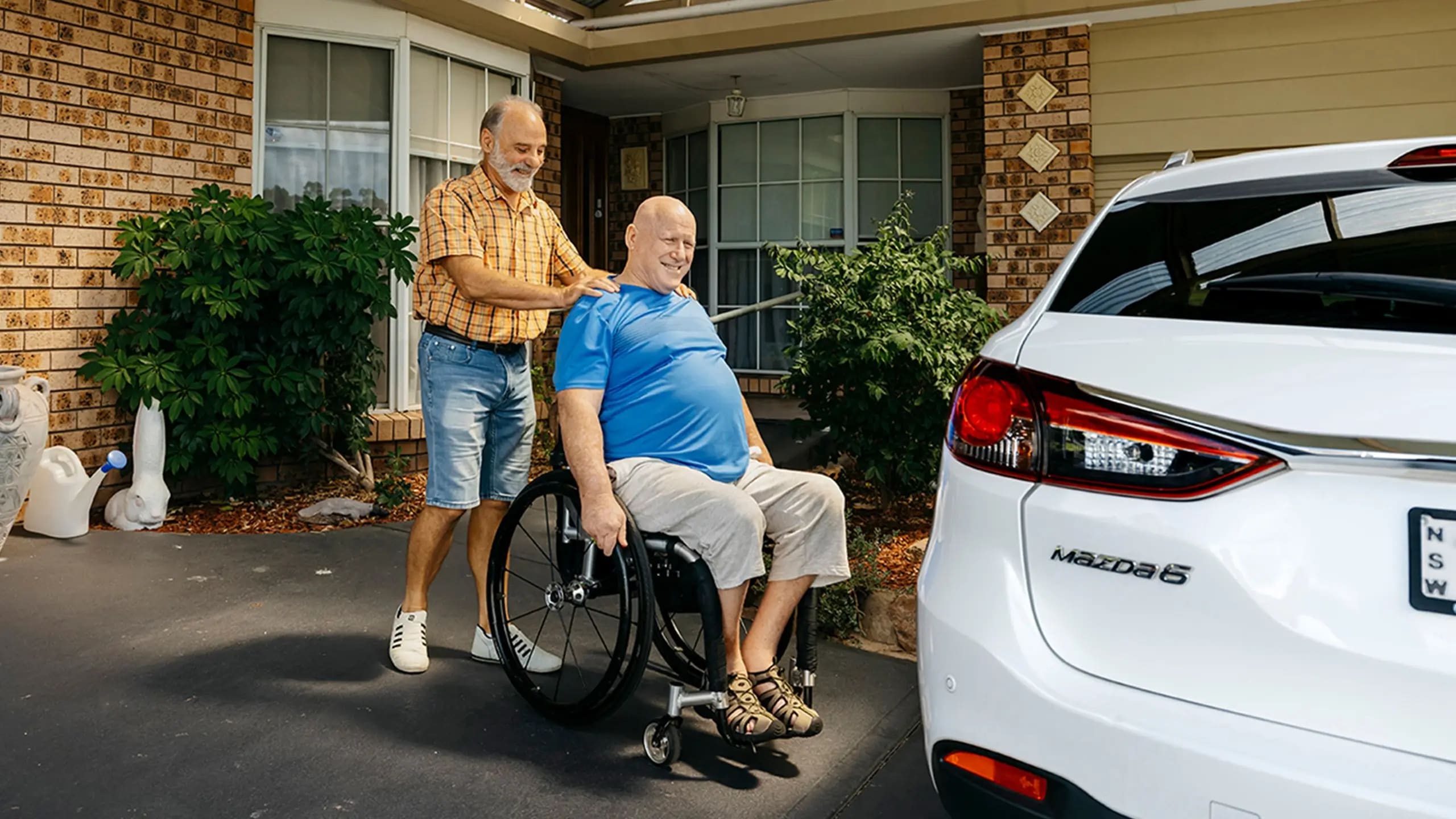 Support worker helps client wheel across the driveway to a car.