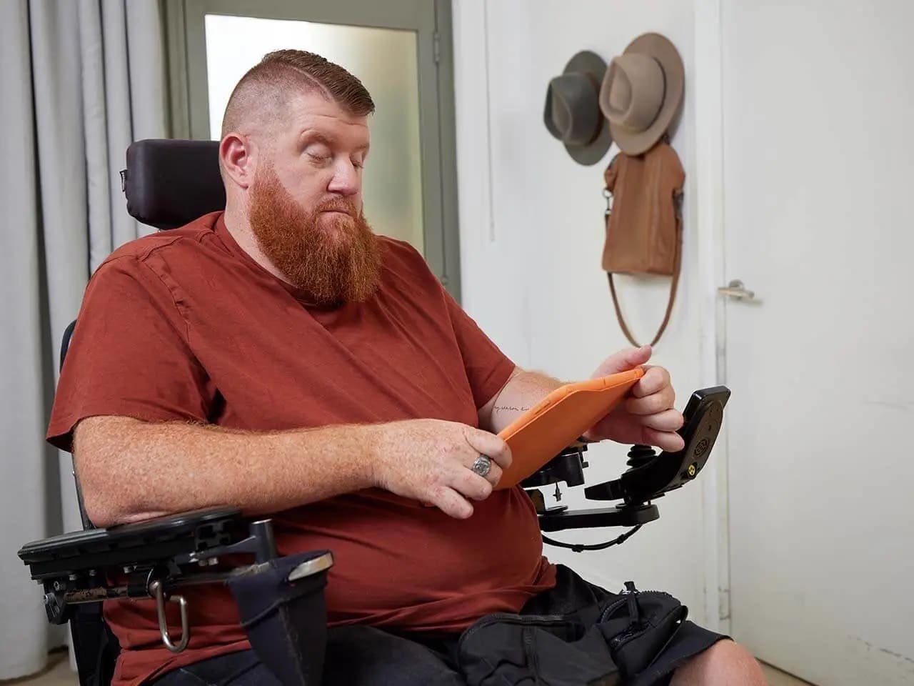 Adult who is in a wheelchair looking at iPad.