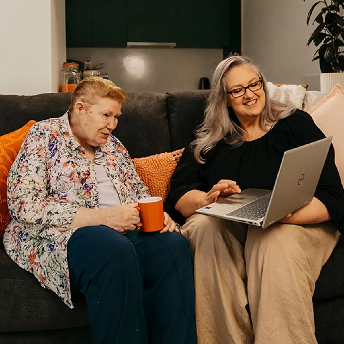 Support coordinator sits with an older client and their laptop to search support workers on Mable.
