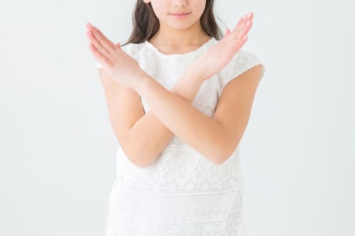 手でNGマークを作る女性