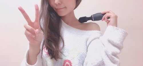 電マを肩に当てピースをする女性