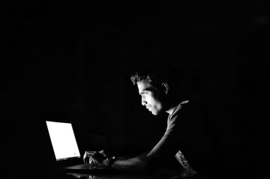 暗闇でPCを眺める男性