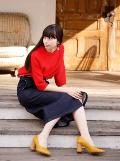 赤いセーターを着て腰掛ける中条あやみ