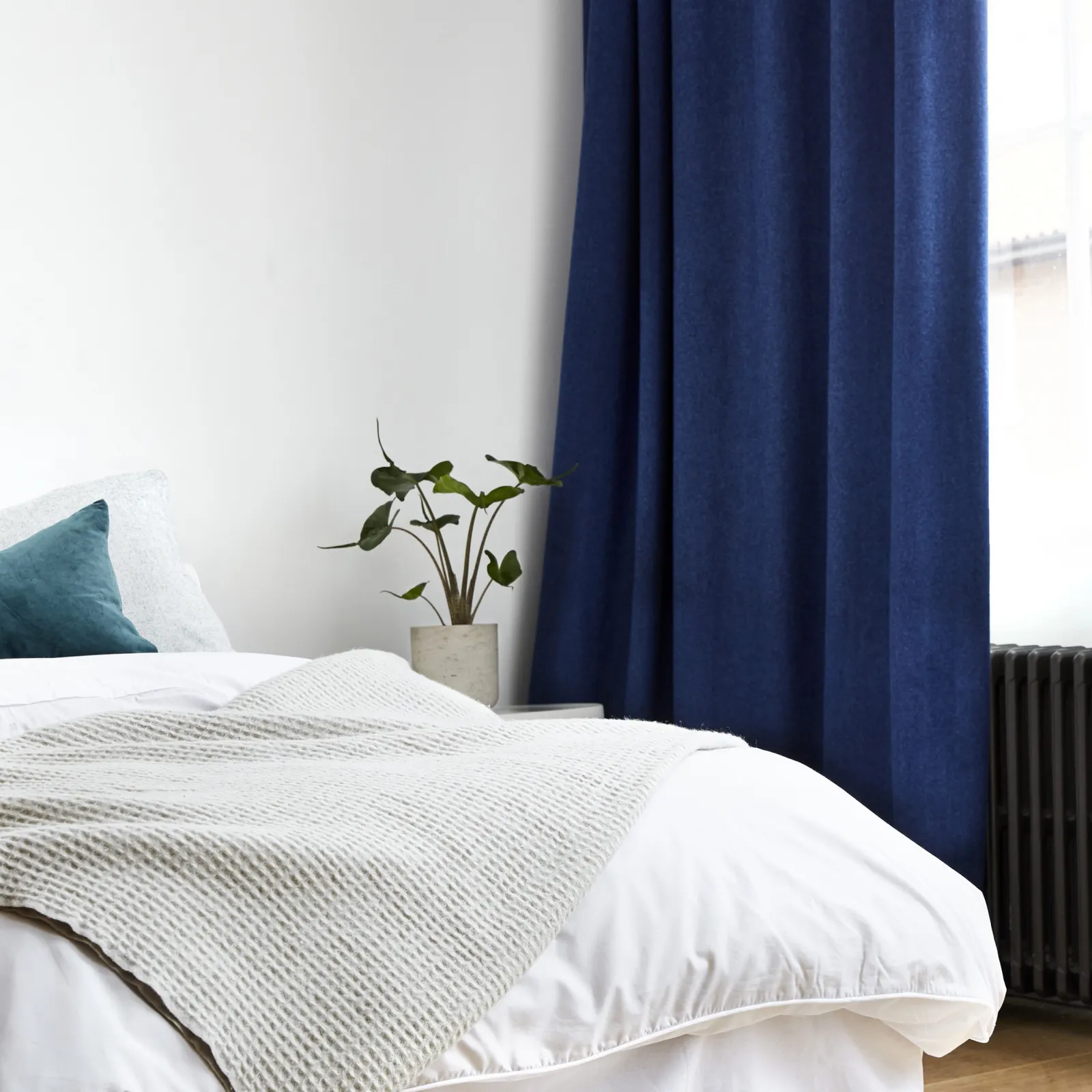 pristine bedroom with white walls and dark blue curtains
