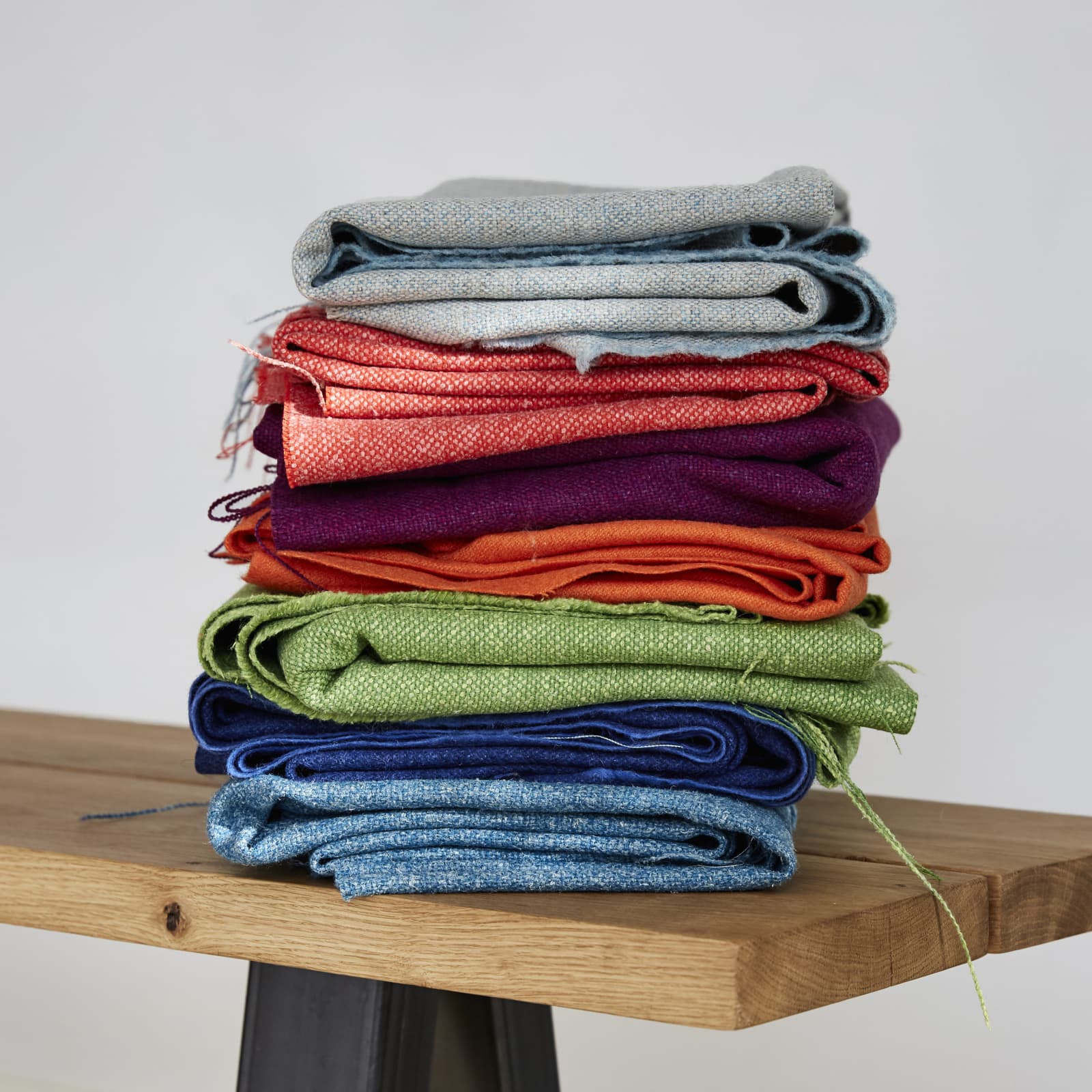 Multi coloured fabrics in a stack on chair