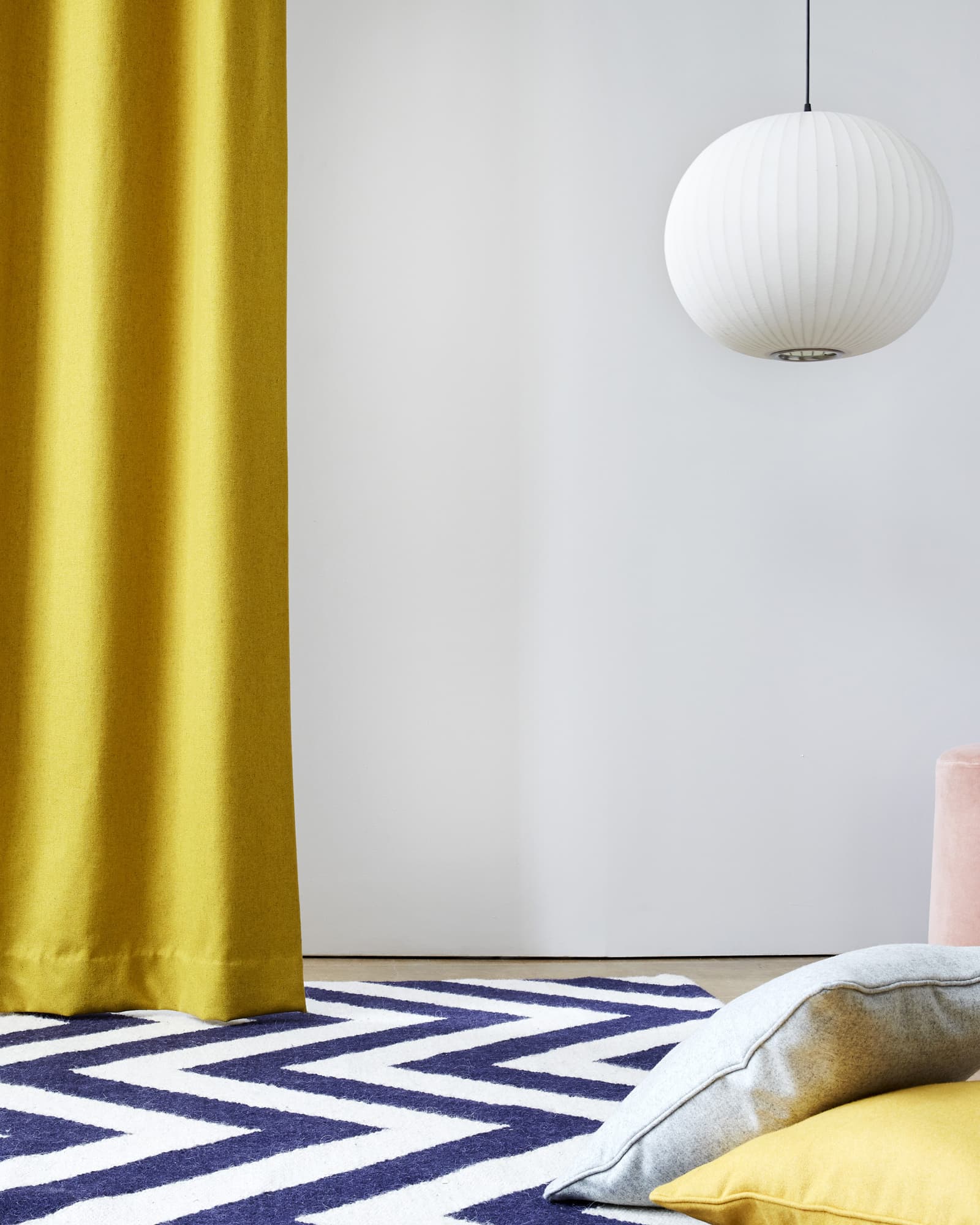 Bright yellow curtains and cushions on a stripped rug