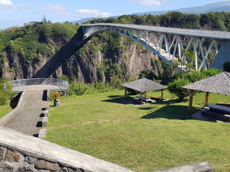 Belvédère aménagé au bord des gorges avec kiosques en bois et pelouse, le pont du Bras de la Plaine en arrière-plan