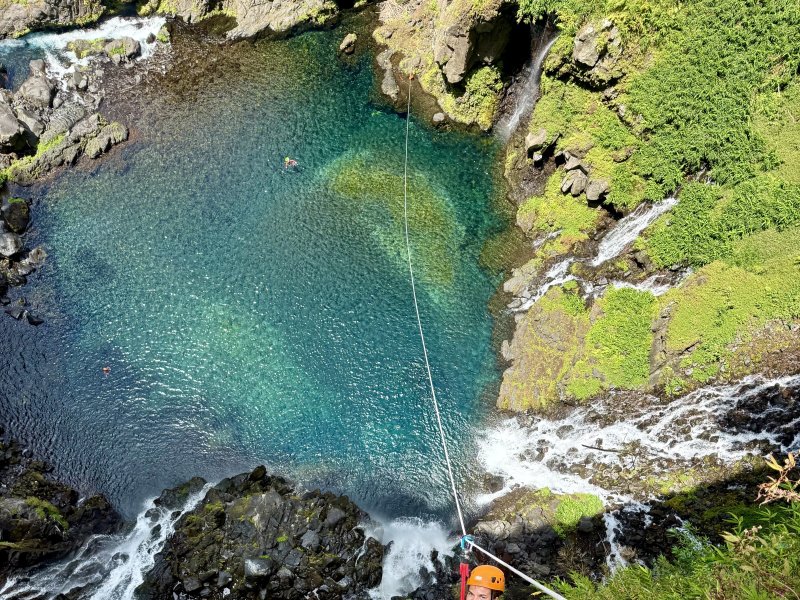 Bassin turquoise vu du haut de la cascade de Grand Galet, une corde tendue qui descend vers l'eau