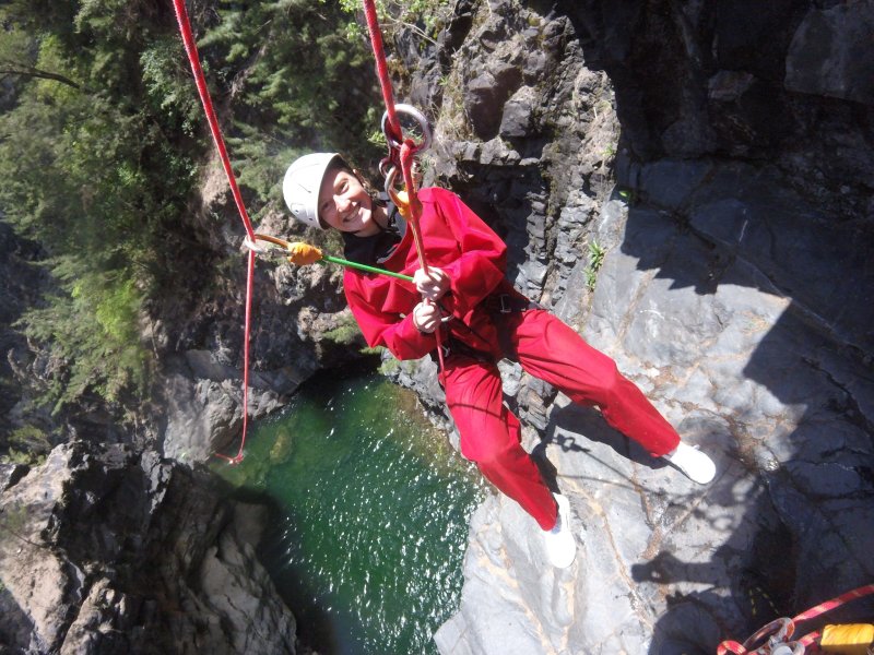 Canyoneuse en rappel rouge dans le canyon de Trou Blanc, bassin vert en contrebas, cirque de Salazie La Réunion