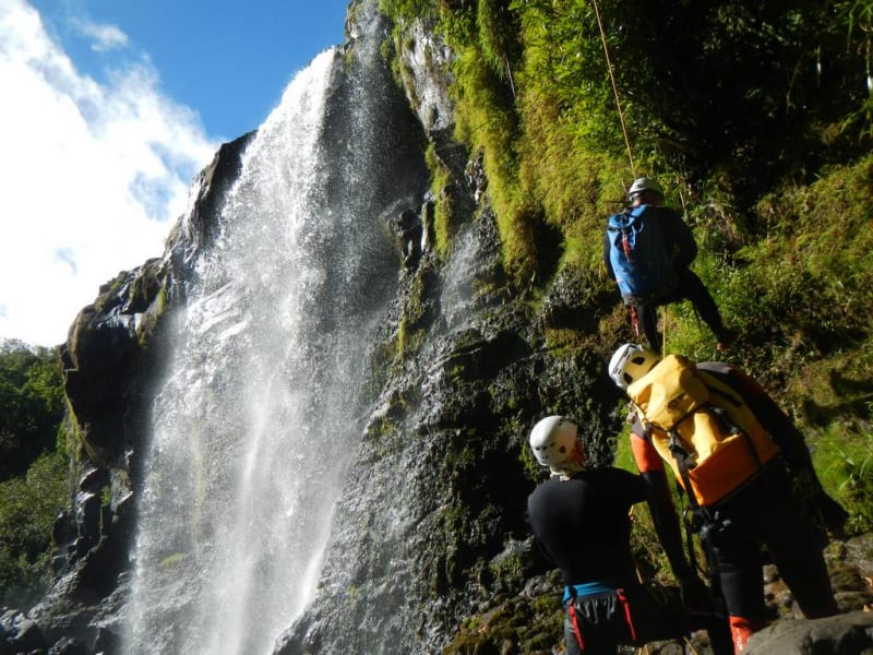 Canyoneurs en rappel au pied d'une cascade dans le canyon de Sainte-Suzanne au Bassin Bœuf, eau claire et parois mousseuses, La Réunion