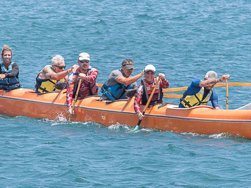 Six pagayeurs en pirogue hawaïenne orange à balancier dans la baie de Saint-Gilles, La Réunion