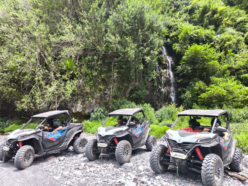 Trois buggies CFMOTO ZForce 950 alignés sur piste devant une cascade et la végétation luxuriante de la forêt de Mont Vert à Saint-Pierre, La Réunion