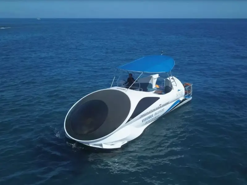 Bateau blanc à auvent bleu doté d'une grande bulle vitrée à l'avant, naviguant sur une mer calme et bleu profond