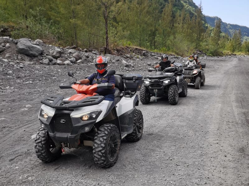 Trois quads en file sur piste graveleuse dans la vallée de la Rivière des Remparts à Saint-Joseph, falaises de basalte et végétation tropicale, La Réunion
