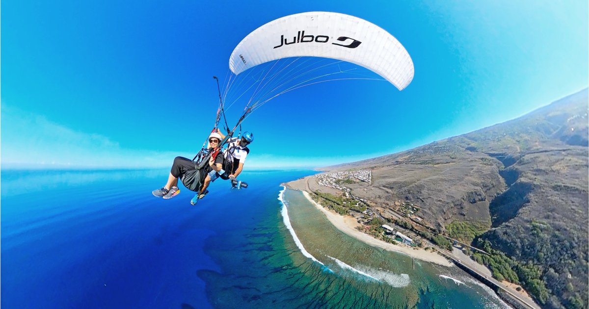 A tandem paraglider flying above the lagoon and coral reef at Saint-Leu, Reunion Island