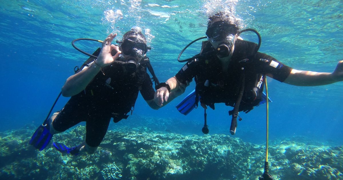 A first dive in Saint-Leu bay, Reunion Island, a supervised diver over the coral seabed