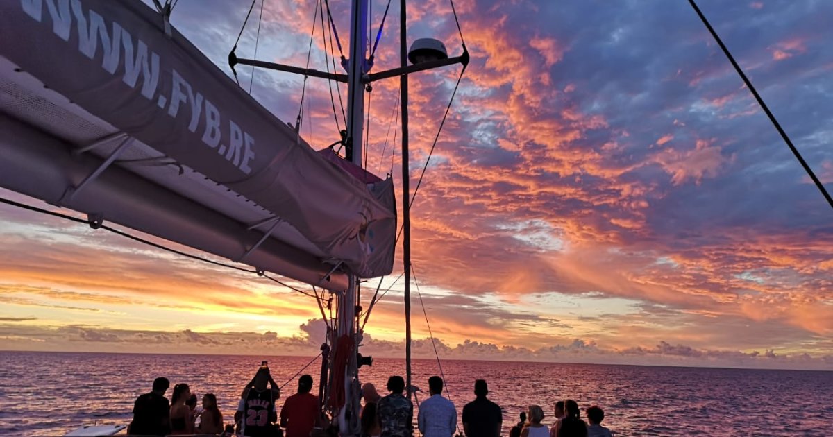 Sunset from the deck of a catamaran in Reunion Island, pink-orange sky and passengers admiring the ocean