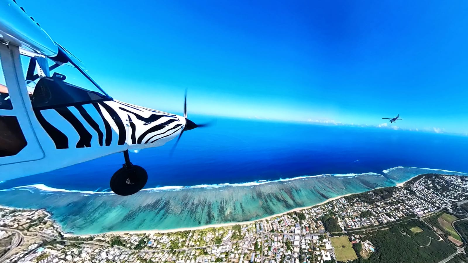 ULM multi-axes en vol au-dessus du lagon turquoise de Saint-Gilles à La Réunion, vue aérienne