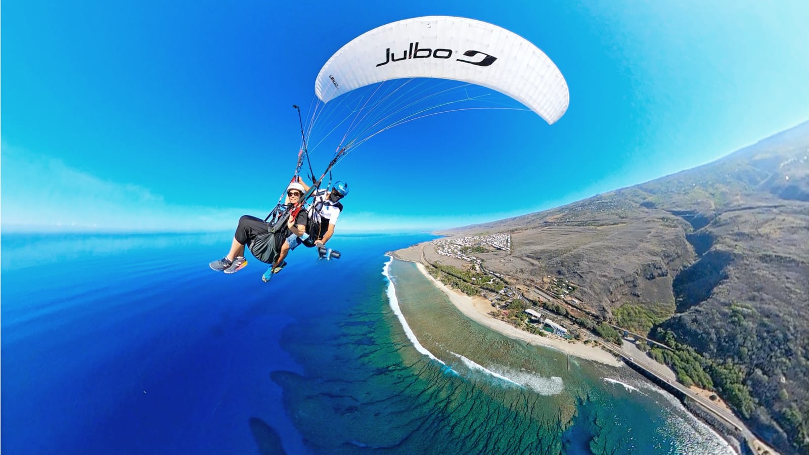 Vol biplace en parapente au-dessus de la baie de Saint-Leu, lagon turquoise en contrebas, La Réunion