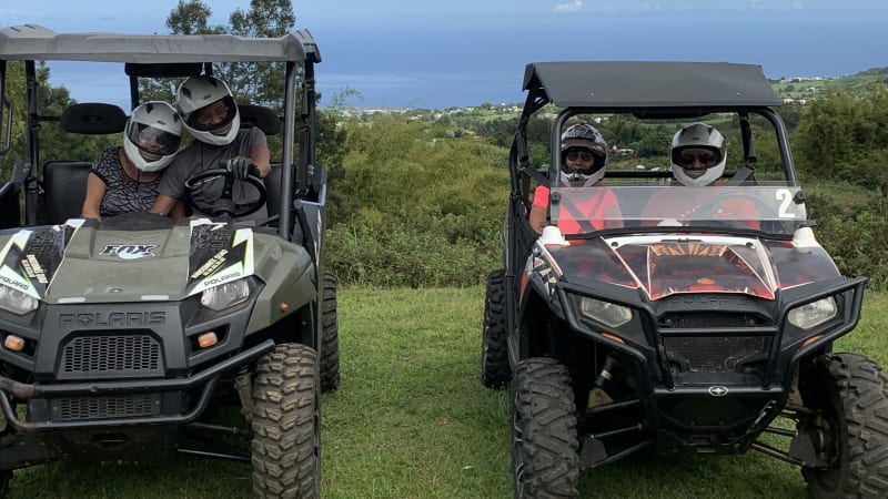 Deux buggies Polaris côte à côte dans l'herbe, occupants casqués, océan à l'horizon