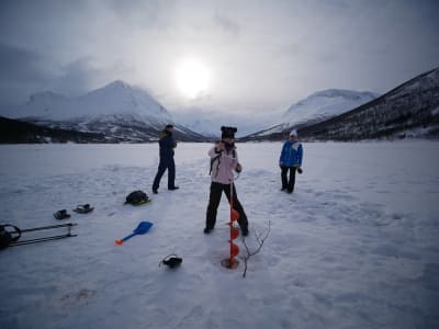 Pesca en hielo en el fiordo congelado y barbacoa cerca de Tromsø