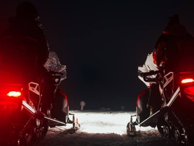 Nordlicht-Schneemobiljagd in der Nähe des Urho Kekkonen Nationalparks von Saariselkä aus