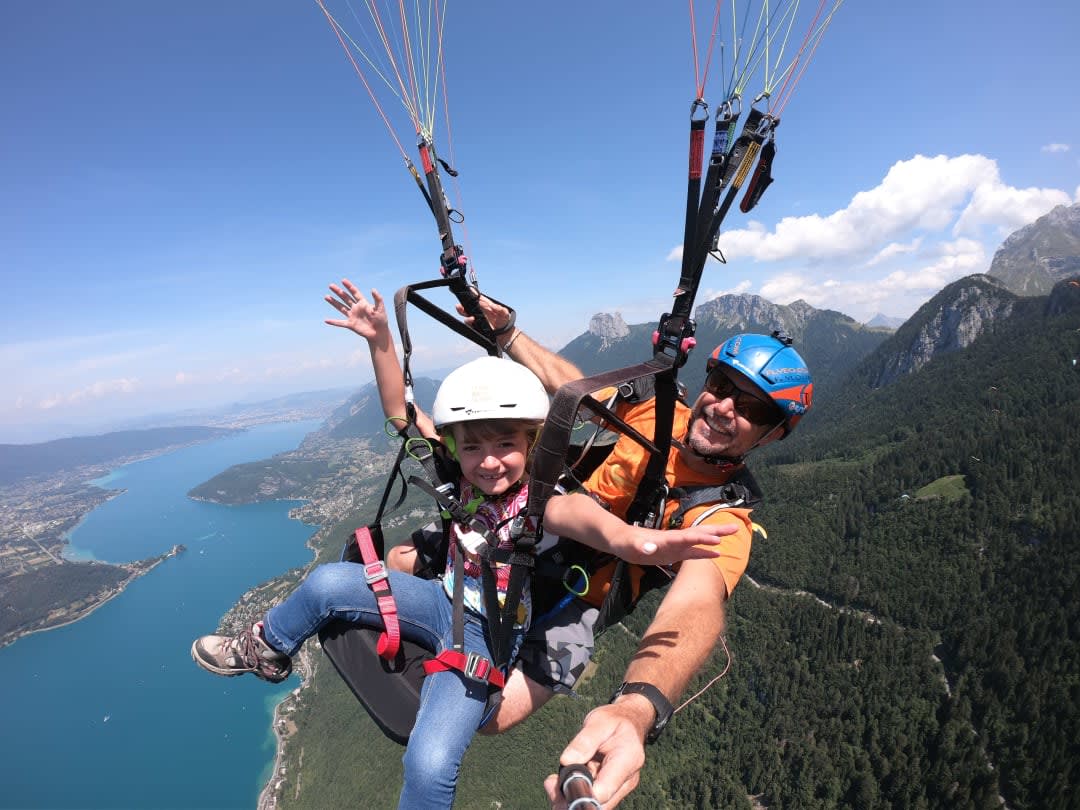 child paragliding above lake annecy