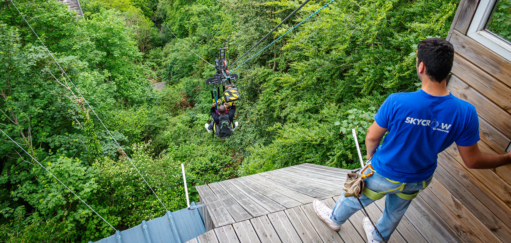 SkyPark staff watch a man with the respective equipment zip-line