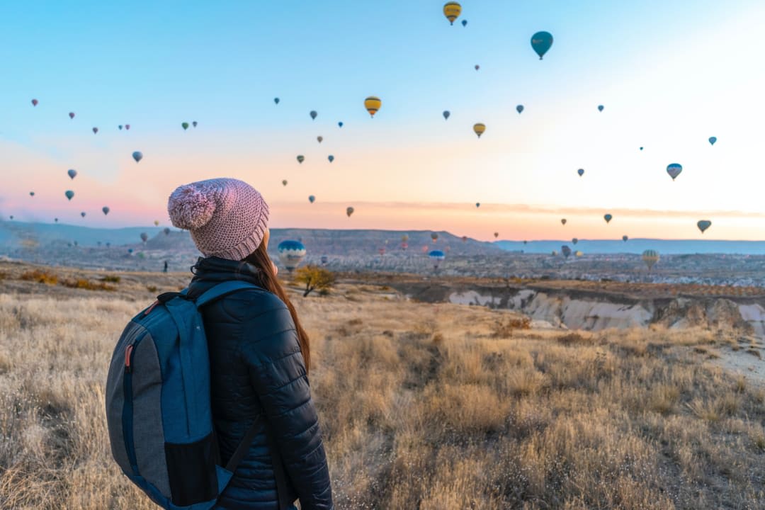 A woman sees a beautiful landscape filled with hot air balloons in the sky