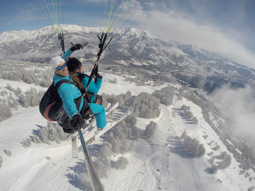 pilot and client ski paragliding in pra loup in winter