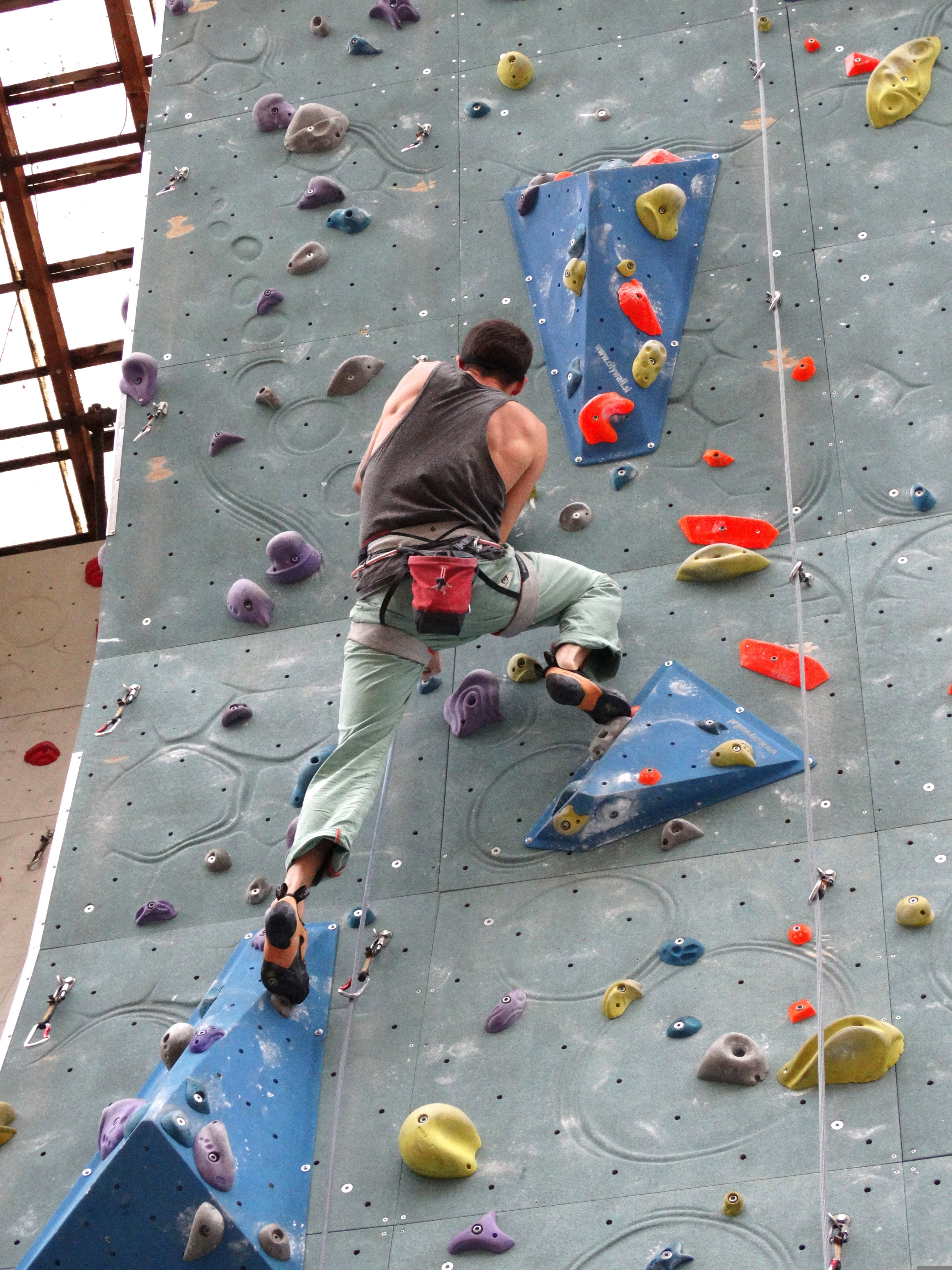 Kletterer, der in einer Kletterhalle einen Boulder erklimmt.