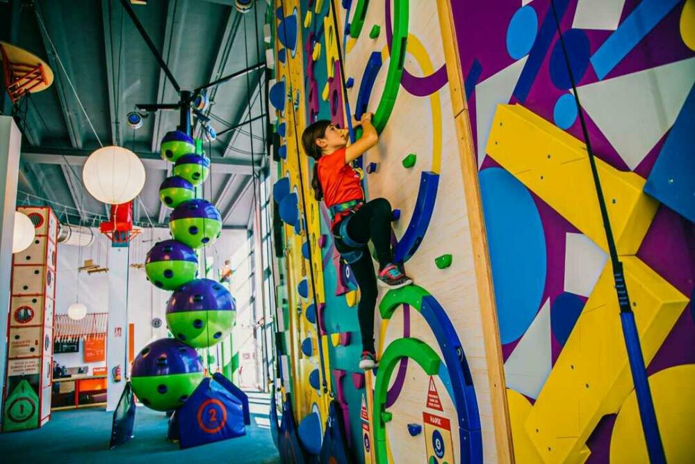 Young girl climbing a boulder in a hall. 