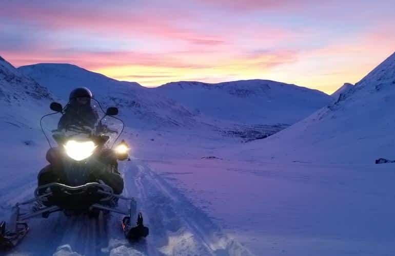 Motos de nieve por la noche durante una excursión de día completo en Tromsø