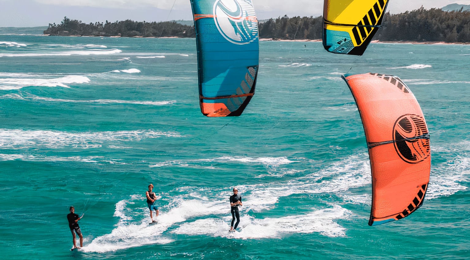 Three kitesurfers on the water