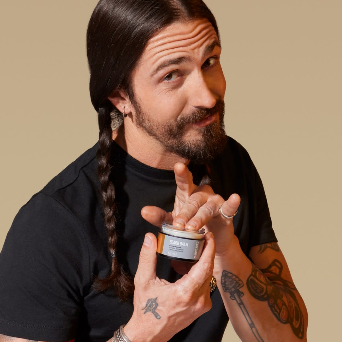 White male model holding a jar of MANSCAPED® Beard Balm