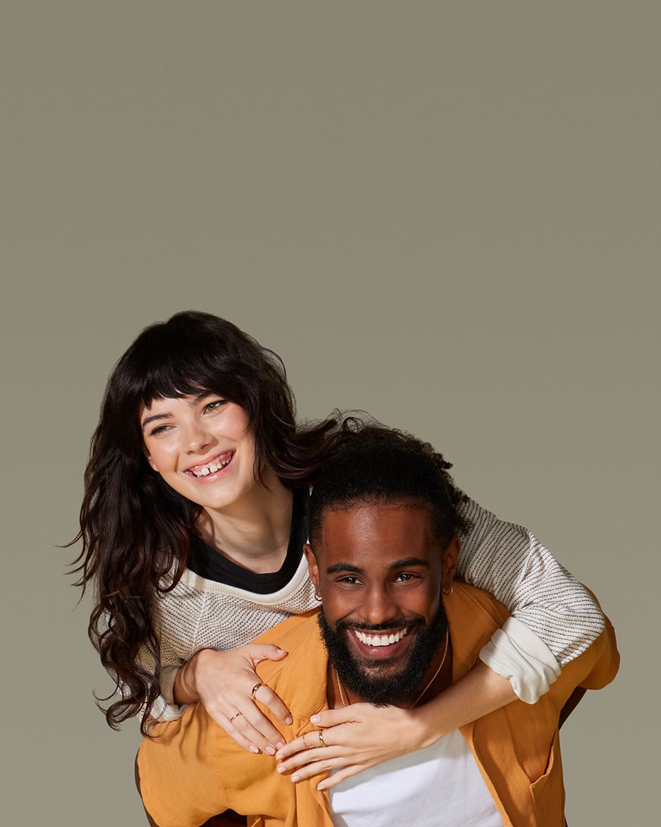 Black male model smiling with white female model piggybacking on him