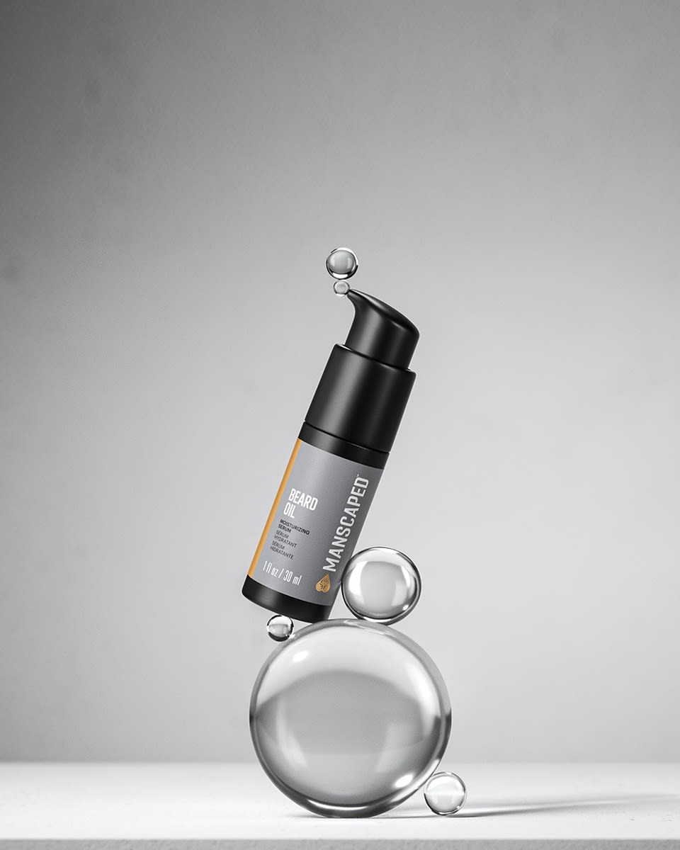 Close up of the Beard Oil pump-bottle sitting on stacked water droplets