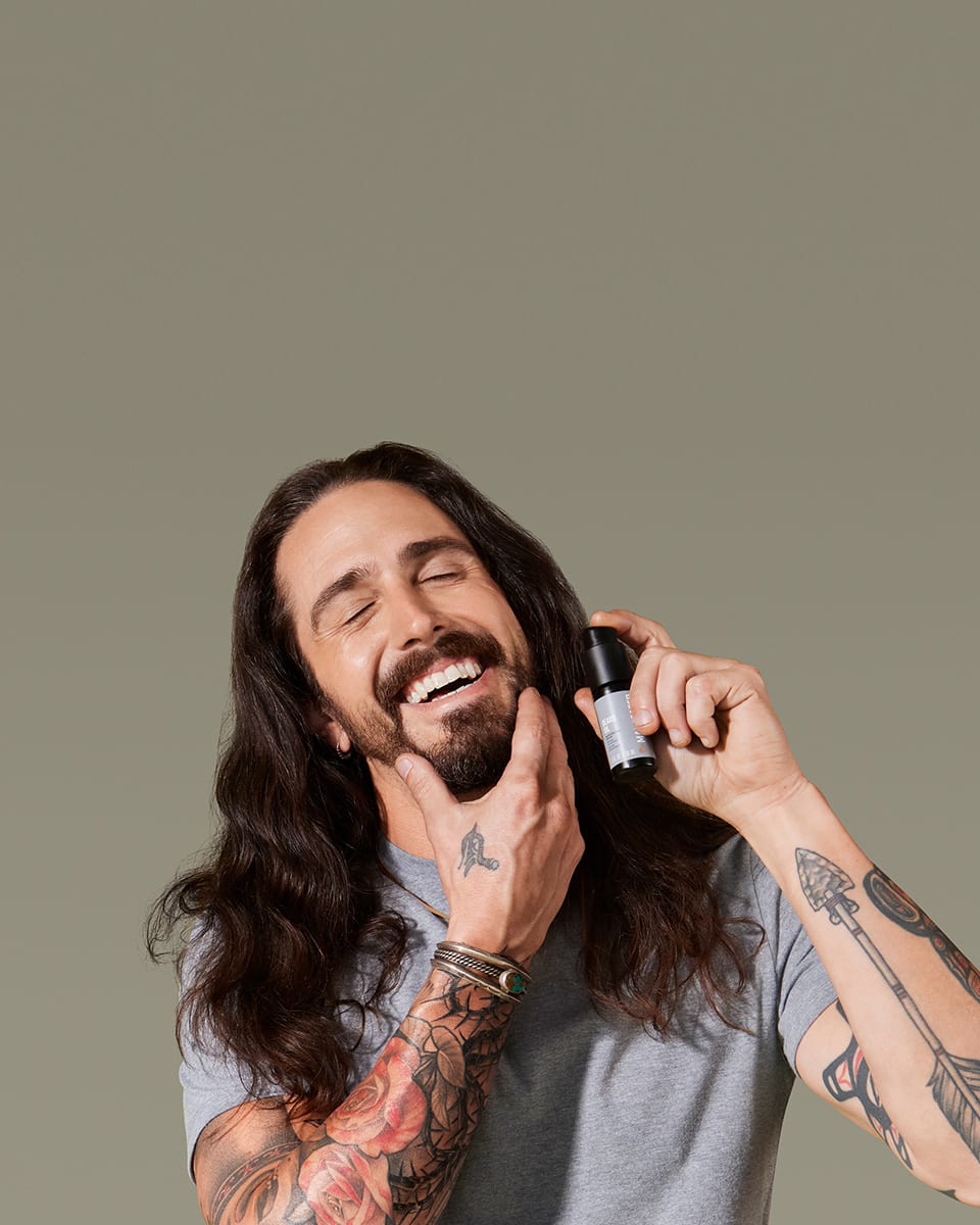 White male model massaging MANSCAPED® Beard Oil into his beard