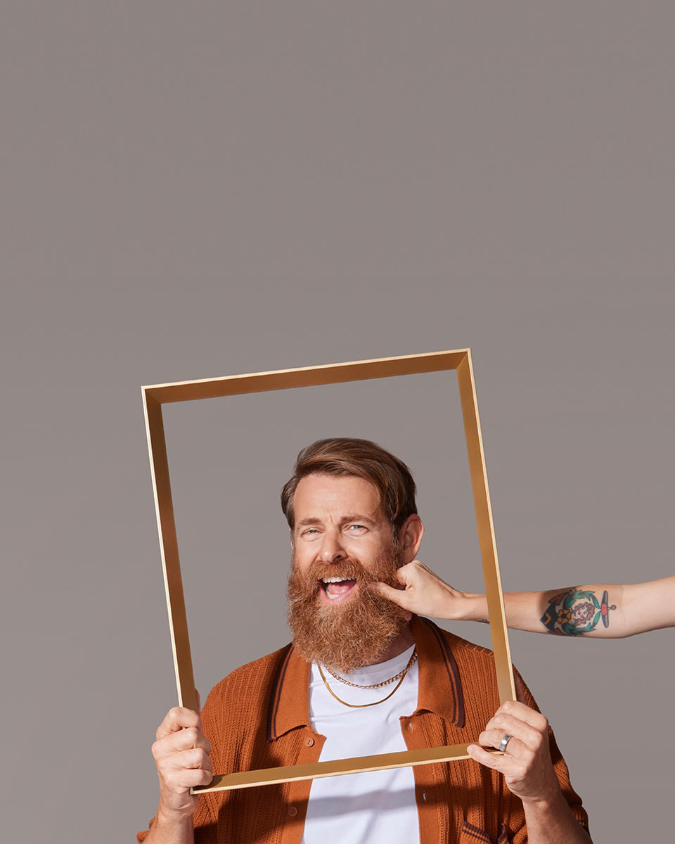 White male model with thick beard having his cheek pinched by female model off-screen