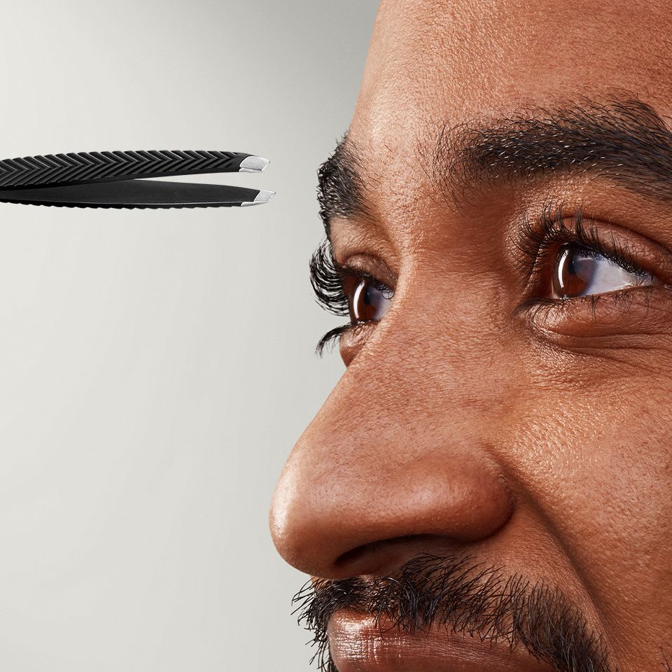 Close-up of The Shears 3.0 tweezers next to a male models eyebrow