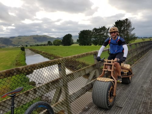 Daniel Strekier with his wooden bike Grace, crossing a small bridge