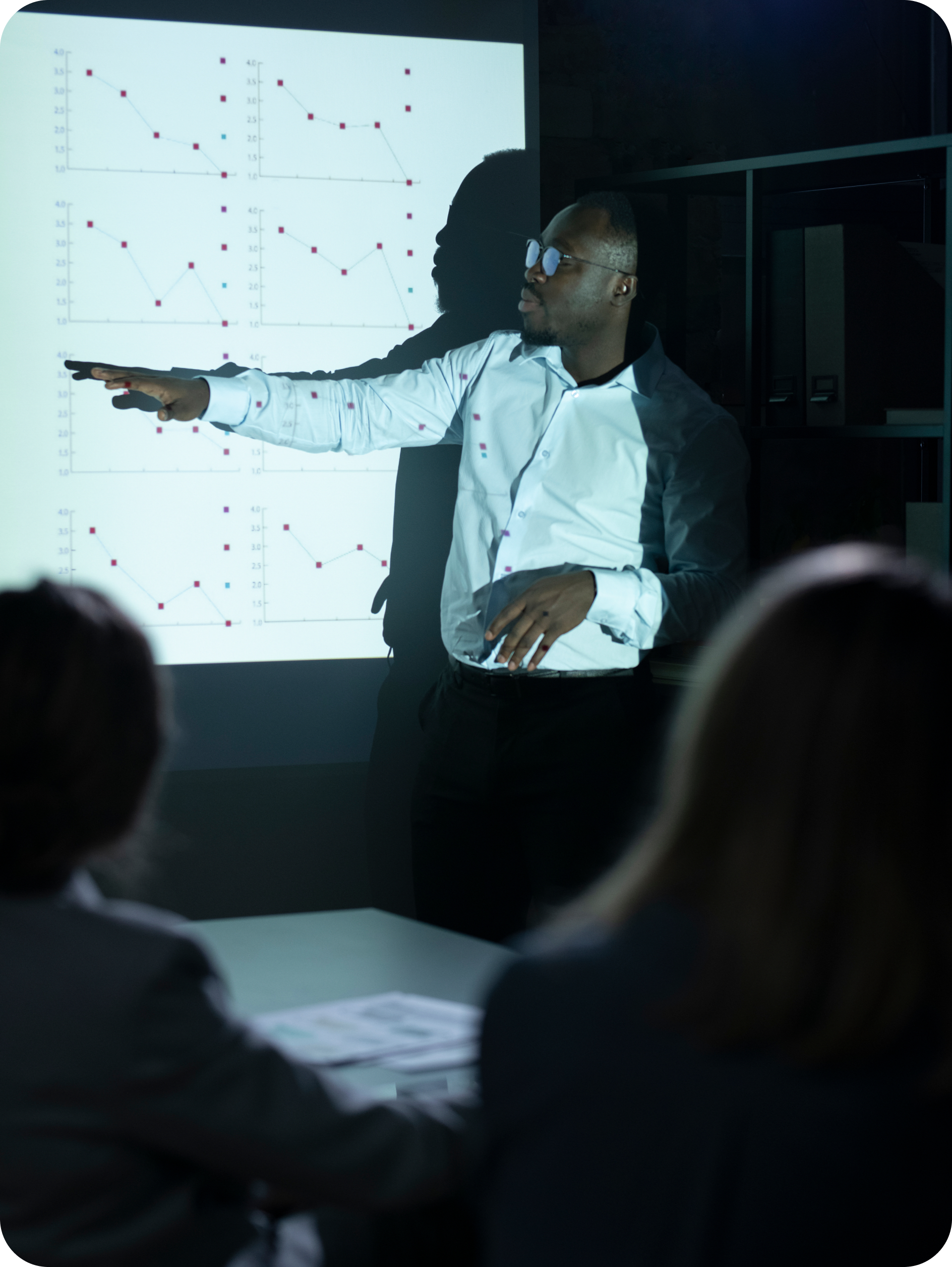 Black man pointing to a screen explaining to a crowd